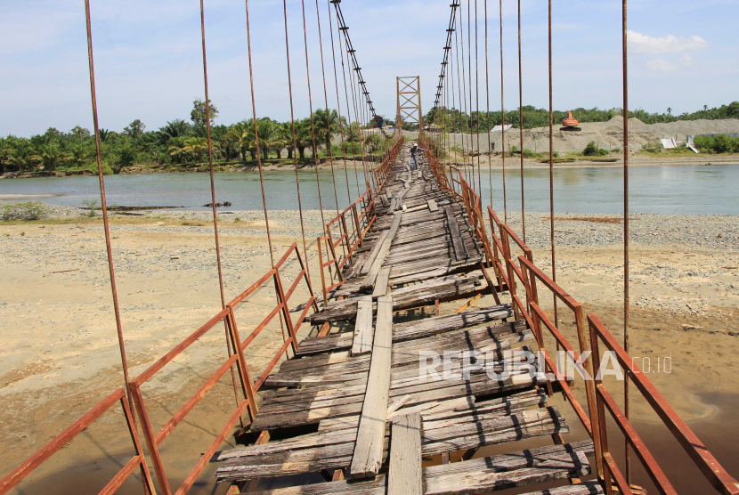 Warga berjalan di atas jembatan gantung yang rusak di Aceh Barat. Cawapres Muhaimin Iskandar alias Cak Imin janji akan memperpanjang dana otsus Aceh.