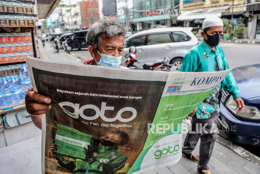 Seorang pria membaca koran dengan iklan yang menunjukkan merger antara Gojek dan Tokopedia di Medan, Sumatera Utara, Selasa (18/5). Perusahaan ride hailing Gojek dan perusahaan e-commerce Tokopedia telah mengumumkan merger dan membentuk perusahaan bernilai miliaran dolar, GoTo Group.