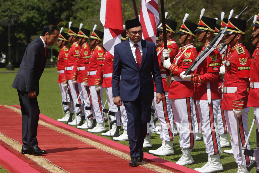 Perdana Menteri baru Malaysia Anwar Ibrahim (tengah) didampingi Presiden Indonesia Joko Widodo saat meninjau pengawal kehormatan di Istana Kepresidenan di Bogor,  9 January 2023.