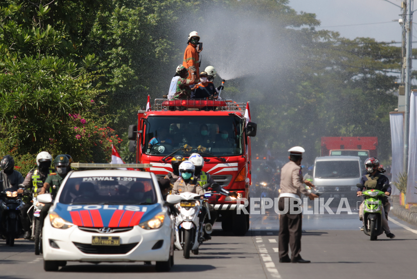 Petugas menyemprotkan cairan disinfektan di Jalan Kedung Cowek, Surabaya, Jawa Timur, Selasa (31/3/2020). Penyemprotan disinfektan di akses jalan menuju ke Jembatan Suramadu itu untuk mencegah penyebaran COVID-19
