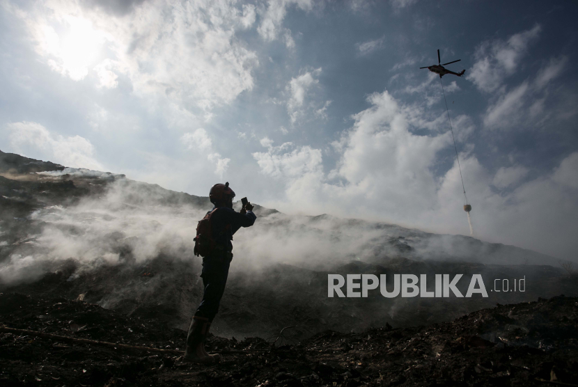 Petugas damkar mengamati helikopter BNPB menumpahkan air untuk memadamkan kebakaran tumpukan sampah di TPA Putri Cempo, Solo, Jawa Tengah.
