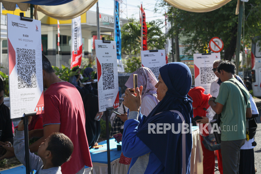 Pengunjung memindai kode Quick Response Code Indonesian Standard (QRIS) pada acara Pekan QRIS Nasional 2023 saat Car Free Day (CFD) di Banda Aceh, Aceh, Ahad (20/8/2023). Pekan QRIS Nasional 2023 tersebut merupakan upaya BI mengkampanyekan penggunaan QRIS sebagai alat pembayaran non tunai di tengah masyarakat dengan target 45 juta pengguna baru dan 1 miliar transaksi QRIS pada tahun 2023 secara nasional.  