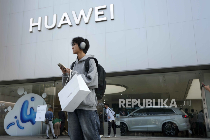 A customer carries his purchased Huawei product stands outside a Huawei store after he attending the Huawei new product launch conference, in Beijing, Monday, Sept. 25, 2023. 