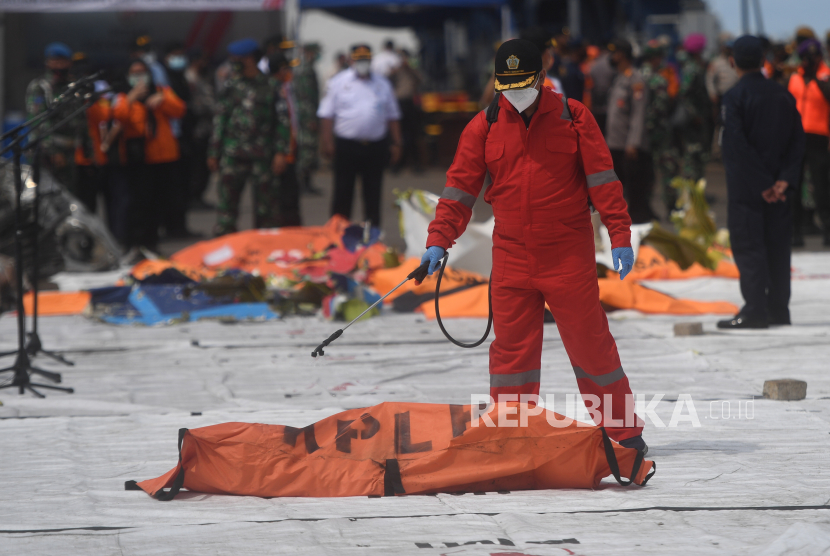 Petugas menyemprotkan disinfektan ke kantong jenazah korban pesawat Sriwijaya Air SJ-182 ydi Dermaga JICT, Jakarta Utara, Selasa (12/1).