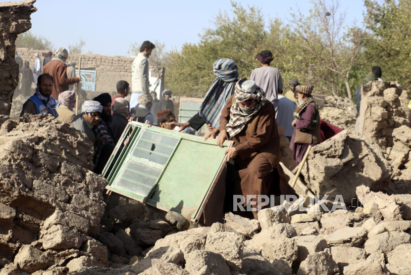 Warga mencari sisa-sisa barang yang dapat diselamatkan setelah gempa bumi di distrik Zenda Jan di provinsi Herat, Afghanistan barat, Ahad, (8/10/2023). 