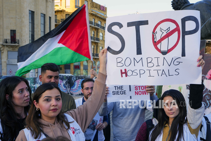 Anggota kelompok kemanusiaan internasional Doctors Without Borders memegang plakat dan bendera Palestina selama protes yang menyerukan diakhirinya perang di Gaza dan gencatan senjata segera.