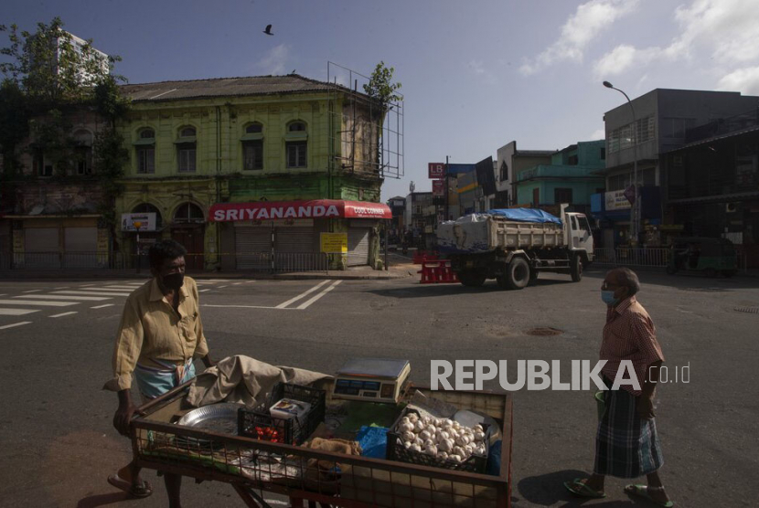 Seorang pedagang mendorong gerobaknya saat melintasi jalan di Kolombo, Sri Lanka.