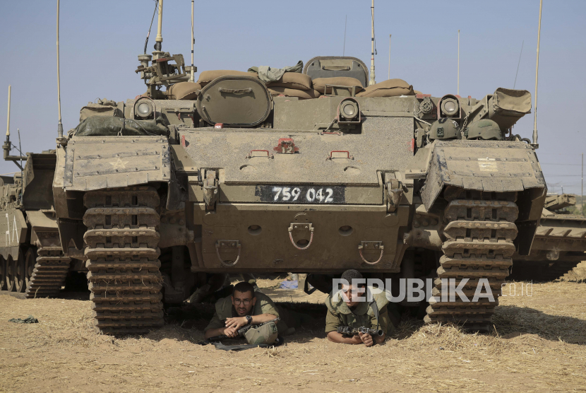 Tentara Israel berlindung di bawah kendaraan lapis baja saat sirene membunyikan peringatan roket masuk dari Jalur Gaza di dekat perbatasan Israel-Gaza selatan Israel, Kamis, 20 Mei 2021.