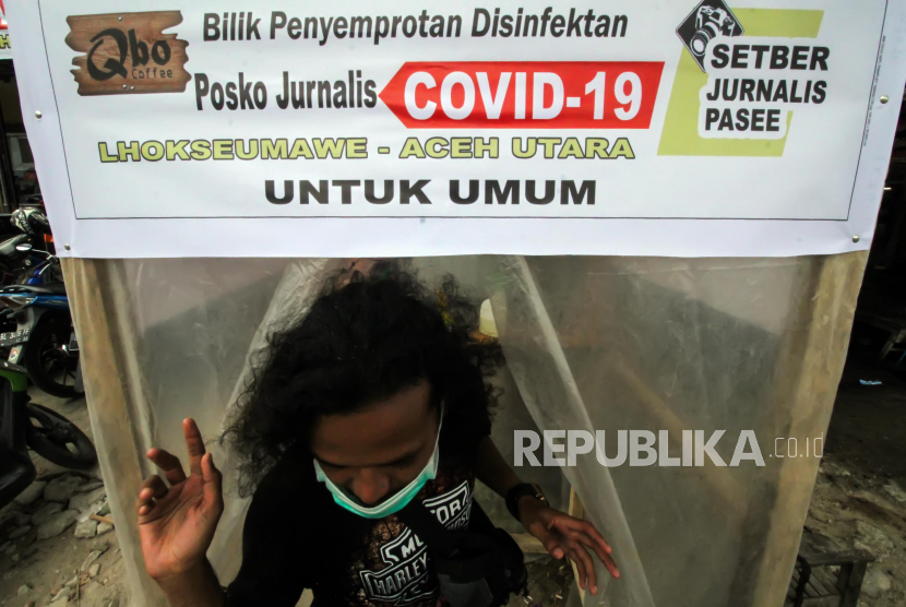 Warga keluar bilik disinfektan  Posko Jurnalis Peliput Corona di Lhokseumawe, Aceh, Kamis (26/3/2020). Bilik penyemprotan cairan disinfektan dan hand sanitizer yang dibangun swadaya wartawan daerah untuk umum itu untuk membantu upaya warga mencegah penyebaran COVID-19, pasca diumumkan hasil laboratorium seorang warga Lhokseumawe pasien dalam pengawasan (PDP) yang meninggal dunia di Rumah Sakit Umum Zainal Abidin (RSUZA) Banda Aceh pada Senin (23/3/2020) dan dinyatakan positif  terserang virus corona