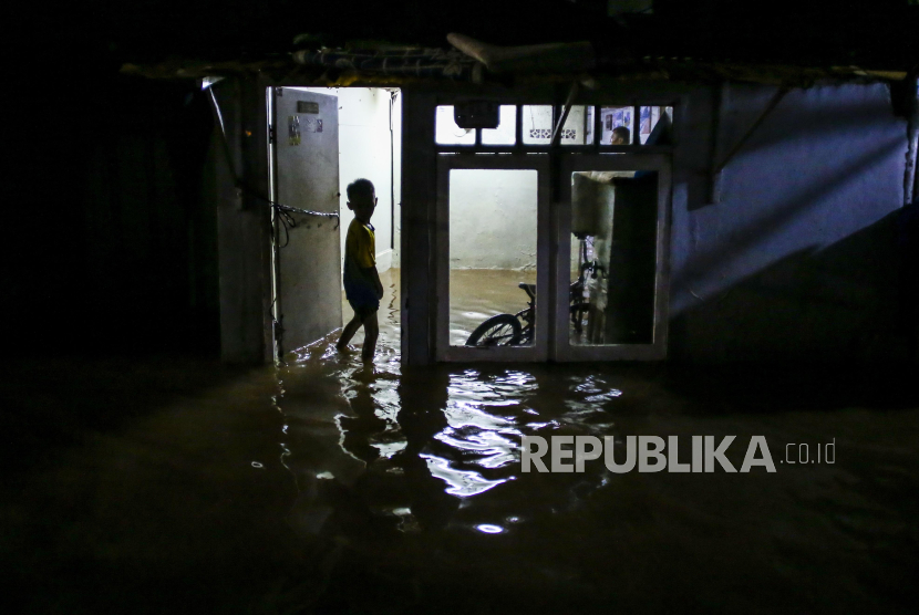 Seorang anak memasuki rumahnya yang terendam banjir di kawasan Cilandak, Jakarta.