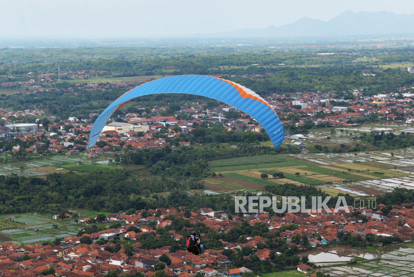Wisatawan mencoba sensasi terbang tandem dengan atlet paralayang di objek wisata paralayang Gunung Panten, Majalengka, Senin (15/4/2024). 
