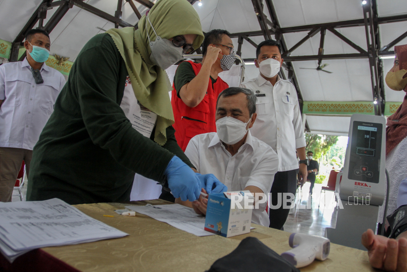 Gubernur Riau Syamsuar memeriksa kondisi kesehatan sebelum menerima suntikkan vaksin dosis ketiga di Pekanbaru, Riau, Rabu (12/1/2022). Pemerintah Provinsi Riau memulai program vaksinasi lanjutan (booster) dengan prioritas Lansia usia diatas 60 tahun. 