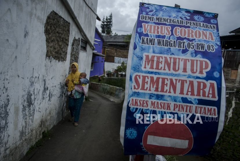 Warga melintasi spanduk sosialisasi protokol kesehatan pandemi COVID-19 di kawasan pemukiman Kota Bandung, Jawa Barat, Rabu (3/2/2021). Pemerintah kembali berencana menerapkan optimalisasi Pemberlakuan Pembatasan Kegiatan Masyarakat (PPKM) dengan pendekatan tingkat lokal mulai dari RT, RW, kampung hingga desa guna efektivitas dalam memutus mata rantai penularan COVID-19. 