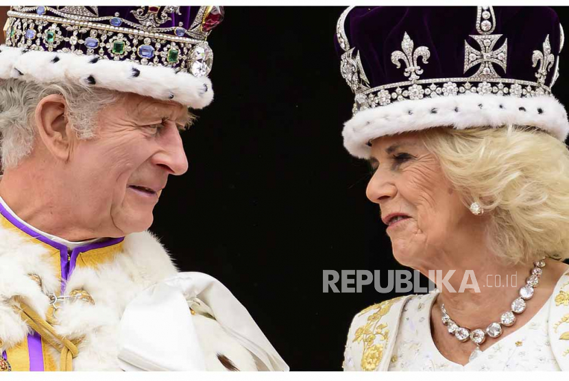 Raja Inggris Charles III dan Ratu Camilla saling memandang saat mereka berdiri di balkon Istana Buckingham setelah penobatan mereka, di London, Sabtu (6/5/2023). Charles dan Camilla menyapa penonton melalui video American Idol.