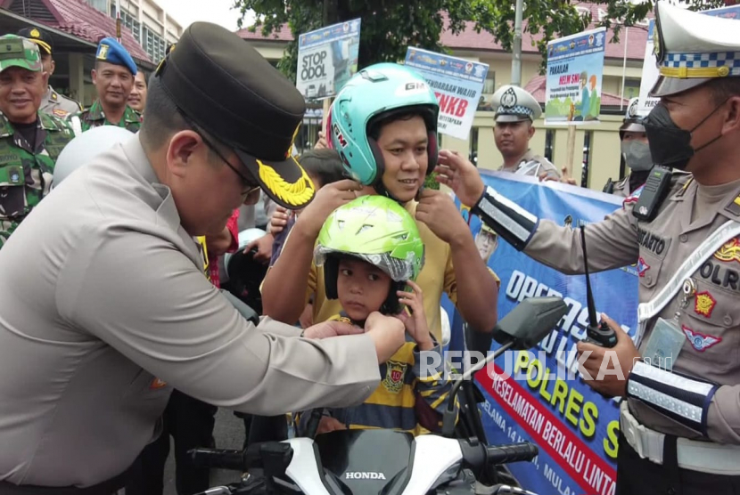 Kapolres Semarang, AKBP Achmad Oka Mahendra, mengenakan helm kepada seorang anak, pada kampanye keselamatan berlalu lintas yang dilaksanakan dalam rangka Operasi Keselamatan Lalu Lintas Candi (OKLC) 2023, di depan Mapolres Semarang, di Ungaran, Kabupaten Semarang, Selasa (7/2).