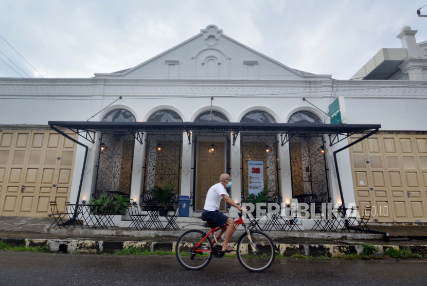 Warga melintasi sebuah kafe kekinian di kawasan Kota Tua Batang Arau, Padang, Sumatera Barat, Jumat (28/5/2021). Pemkot Padang akan menjadikan kawasan kota tua Batang Arau sebagai kawasan ekonomi kreatif dengan pemanfaatan gedung-gedung tua menjadi kafe kekinian dan UMKM sehingga wisatawan bisa berwisata sekaligus menikmati kuliner dan oleh-oleh. 