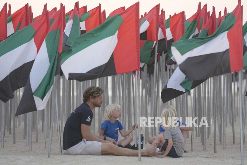 Orang-orang duduk di bawah bendera UEA yang dipajang enam ribu di antaranya untuk merayakan Hari Bendera negara itu di Dubai, Uni Emirat Arab, Sabtu, 4 November 2023. Hari Bendera Emirates secara resmi jatuh pada 3 November.