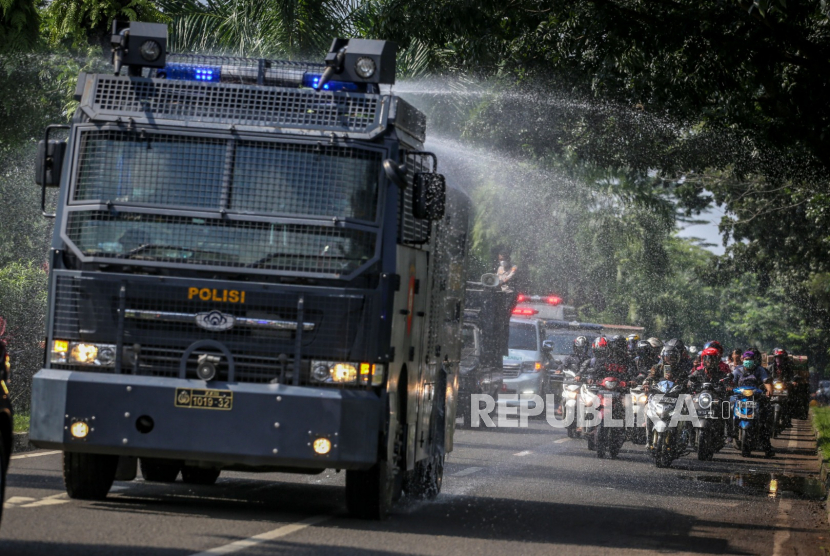 Petugas kepolisian menyemprotkan cairan disinfektan menggunakan mobil Armor Water Canon (AWC).