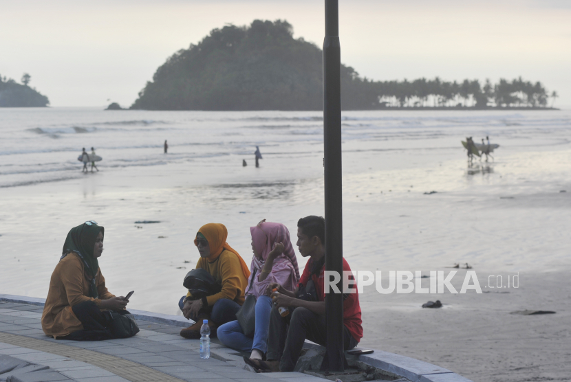 Sejumlah pengunjung duduk di pedestrian pantai di objek wisata Pantai Air Manis, di Padang, Sumatera Barat