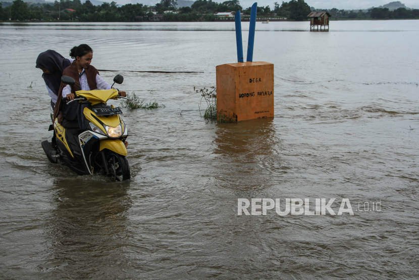 Pengendara motor menerobos banjir di Desa Borong Palala, Kabupaten Gowa, Sulawesi Selatan, Rabu (17/1/2024). Tingginya intensitas curah hujan beberapa hari terakhir mengakibatkan area persawahan dan akses jalan desa di daerah itu terendam banjir. 
