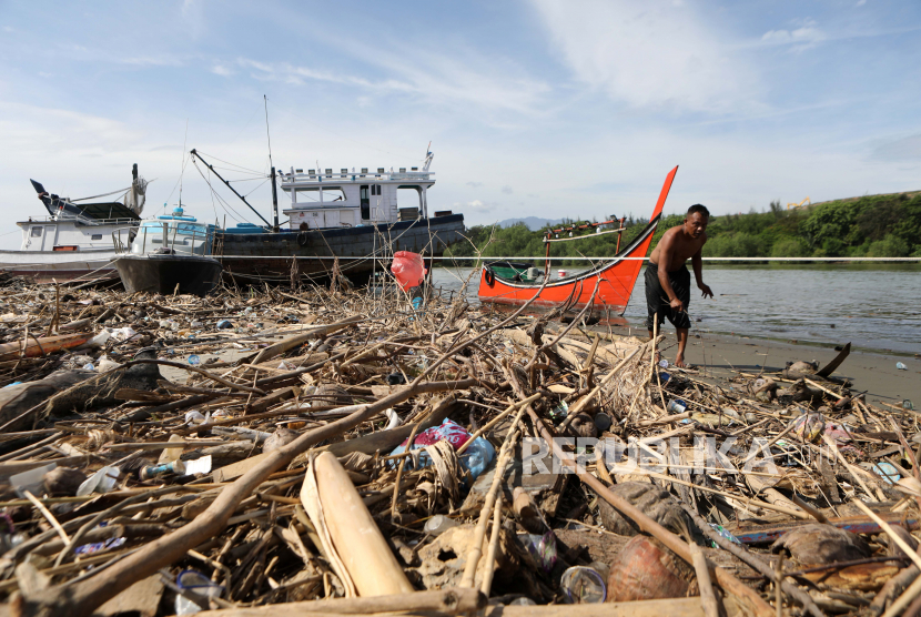 Seorang pria berjalan melewati sampah plastik dan sampah rumah tangga yang terdampar di tepi sungai (ilustrasi). Pemkot Banjarmasin berhasil mengurangi sampah plasti hingga 26,7 persen.