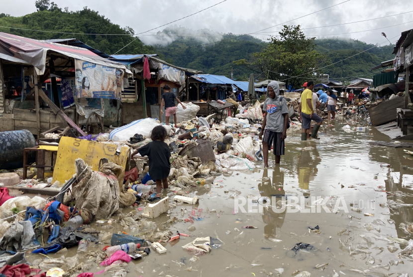 Sejumlah warga melintasi tumpukan sampah akibat banjir di Pasar Youtefa, Abepura, Jayapura, Papua, Ahad (9/1/2022). Aktivitas Pasar Youtefa mulai berjalan kembali pascabanjir yang melanda sejumlah wilayah di Jayapura pada Jumat (7/1/2022). 