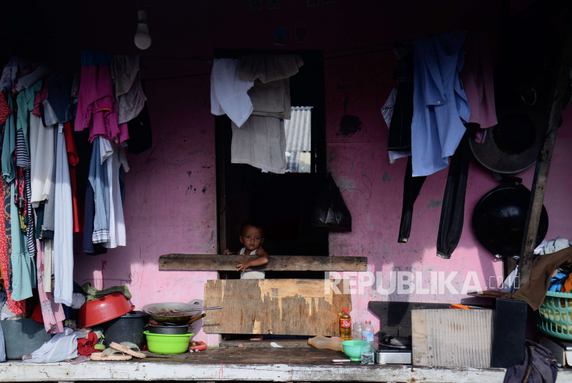 Seorang anak berdiri di depan pintu hunian yang berada di atas laut di kawasan Penjaringan, Jakarta Utara, Senin (30/1/2023). Institute for Development of Economics and Finance (Indef) memperkirakan angka kemiskinan meningkat pada Maret 2023.