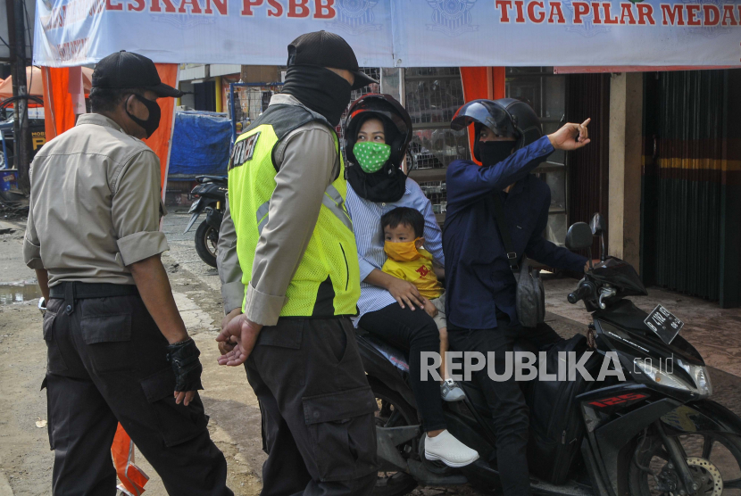 Sejumlah petugas kepolisian mengecek identitas pengendara motor yang melintas di check point PSBB (Pembatasan Sosial Berskala Besar), Bekasi, Jawa Barat, Selasa (28/4). 