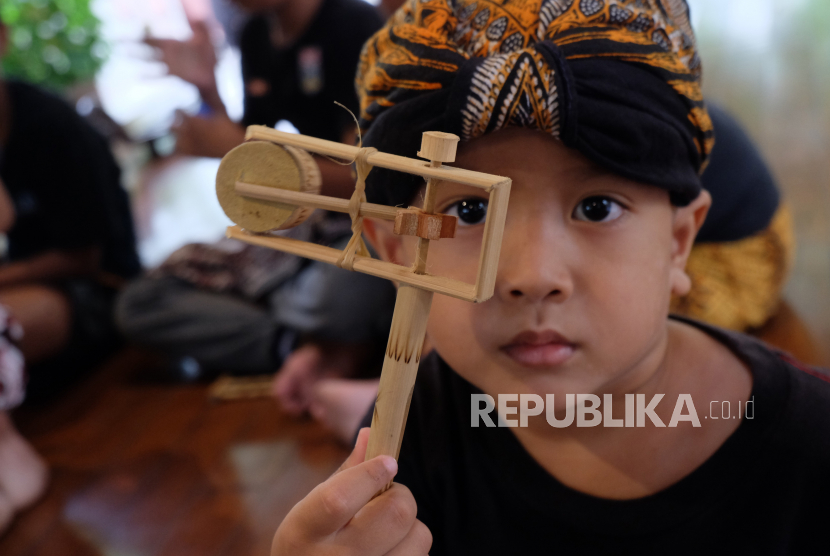 Seorang anak anggota Sanggar Nadinala bermain mainan  othok-othok di Pendapa Sasangka Ayom Java Village, Colomadu, Kabupaten Karanganyar, Jawa Tengah, Jumat (3/2/2023). Latihan rutin yang diikuti anak-anak usia sekolah tersebut digelar untuk mengenalkan permainan tradisional dan seni Budaya Jawa sekaligus mengalihkan ketergantungan anak-anak terhadap gawai.