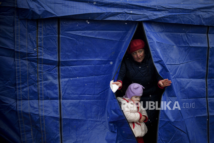 Pengungsi yang melarikan diri dari konflik dari negara tetangga Ukraina keluar dari tenda di perbatasan Rumania-Ukraina, di Siret, Rumania.