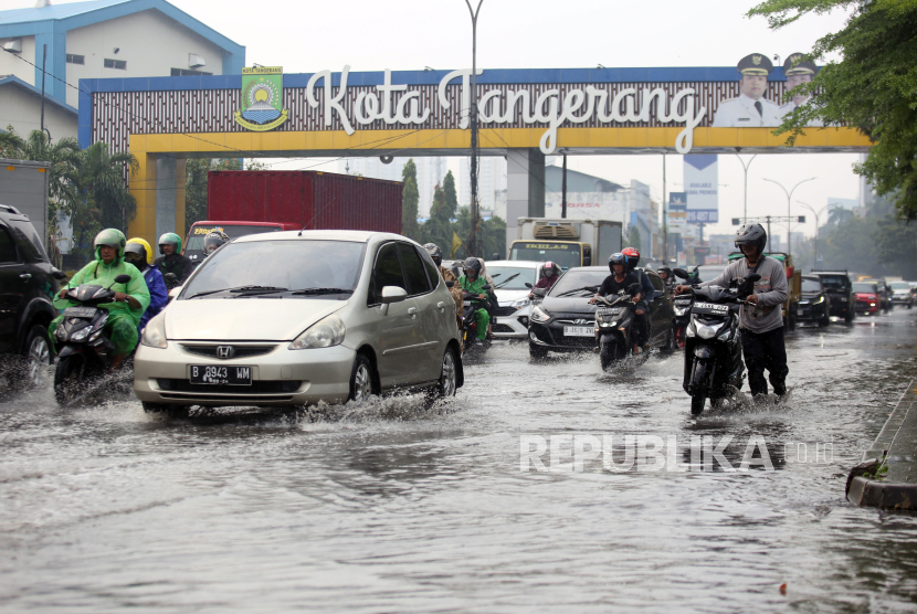 Pengendara motor dan mobil melintasi genangan air yang merendam jalan raya Serpong. Ini tips berkendara menghindari kecelakaan saat hujan.
