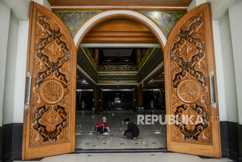 Sejumlah pengurus masjid memasangkan tanda silang untuk membatasi shaf jamaah di Masjid Agung Al-Barkah, Kota Bekasi, Jawa Barat, Kamis (28/5). Pemerintah Kota Bekasi mulai membuka Masjid untuk kegiatan Shalat Jumat di wilayah zona hijau COVID-19 dengan tetap menerapkan protokol kesehatan