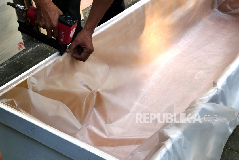 Pemasangan plastik pada peti jenazah khusus Covid-19. PMI Kabupaten Tangerang menyediakan 50 peti jenazah untuk warga yang meninggal saat menjalani isolasi mandiri (isoman) Covid-19.