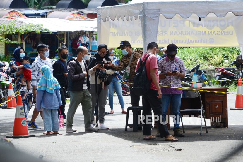 Petugas membimbing pengunjung yang melakukan reservasi online di pintu masuk Taman Hutan Raya H Djuanda (Tahura), Kota Bandung, Ahad (2/1). Sebagai bagian dari penerapan protokol kesehatan saat ini Tahura menerapkan pembatasan berupa kuota kunjungan dan pengunjung juga harus melakukan reservasi secara online. Aturan tersebut sengaja diterapkan guna memberikan kemanan dan kenyamanan bagi para wisatawan di saat pandemi.