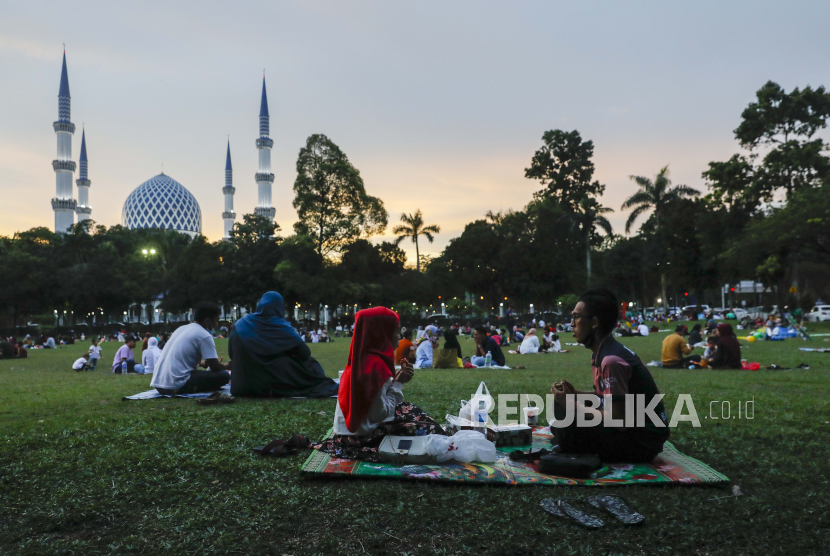 Muslim Malaysia menjaga jarak sosial dan mengenakan masker pelindung wajah berdoa sebelum berbuka puasa di depan masjid di taman umum di Shah Alam, di luar Kuala Lumpur, Malaysia, 25 April 2021.