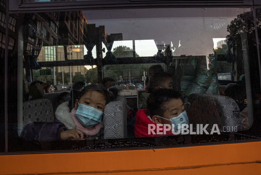  Anak-anak yang mengenakan masker pelindung wajah menunggu di bus untuk dijemput oleh orang tua mereka setelah mereka tiba dari taman kanak-kanak, di Wuhan, China, 31 Desember 2020 (dikeluarkan 01 Januari 2021). Kehidupan di Wuhan, kota di China berpenduduk lebih dari 11 juta, yang hampir setahun lalu menjadi episentrum wabah virus corona, kembali normal. 