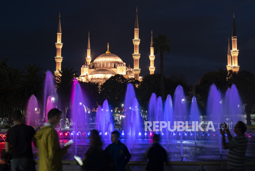 Turis dan penduduk setempat melihat air mancur bercahaya berlatar Sultan Ahmed atau Masjid Biru era Ottoman di Istanbul, Turki, Selasa, (8/8/ 2023).
