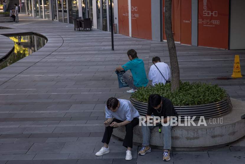  Pemuda Tionghoa bermain di ponsel mereka di kawasan perbelanjaan dan perumahan Sanlitun, di Beijing, Tiongkok, 25 Agustus 2021 (diterbitkan 26 Agustus 2021). Perusahaan teknologi multinasional asal China, Tencent, mengatur ulang strategi M&A untuk lebih fokus membeli saham mayoritas terutama di perusahaan game luar negeri. 
