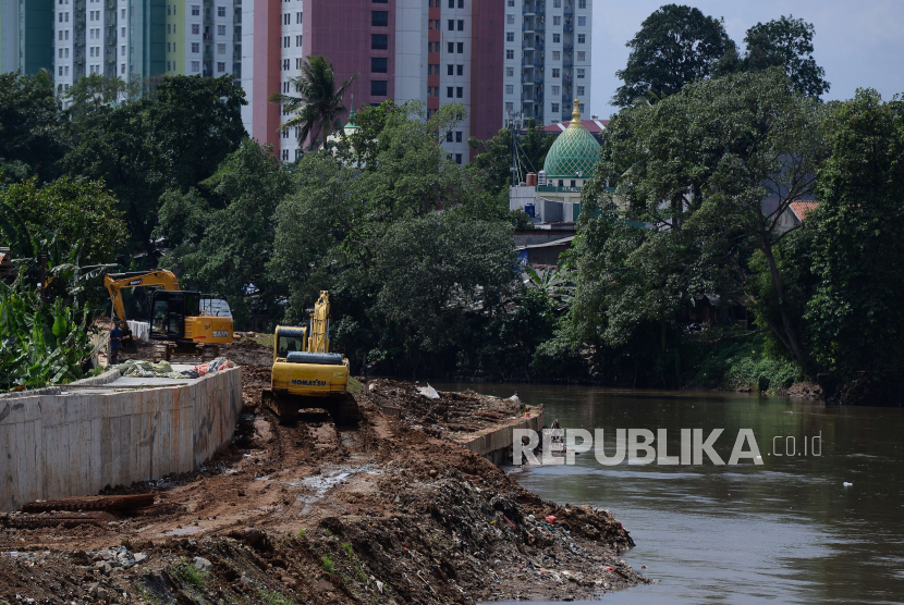 Pekerja menggunakan alat berat menyelesaikan proyek normalisasi Sungai Ciliwung. Pj Gubernur DKI Heru Budi sebut normalisasi Kali Ciliwung dilanjutkan secara bertahap.