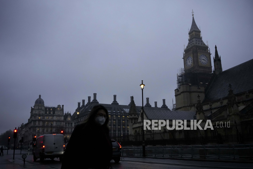  Seorang wanita mengenakan masker wajah untuk mengekang penyebaran virus corona berjalan melewati Menara Elizabeth, yang dikenal sebagai Big Ben, dan Gedung Parlemen, di London.