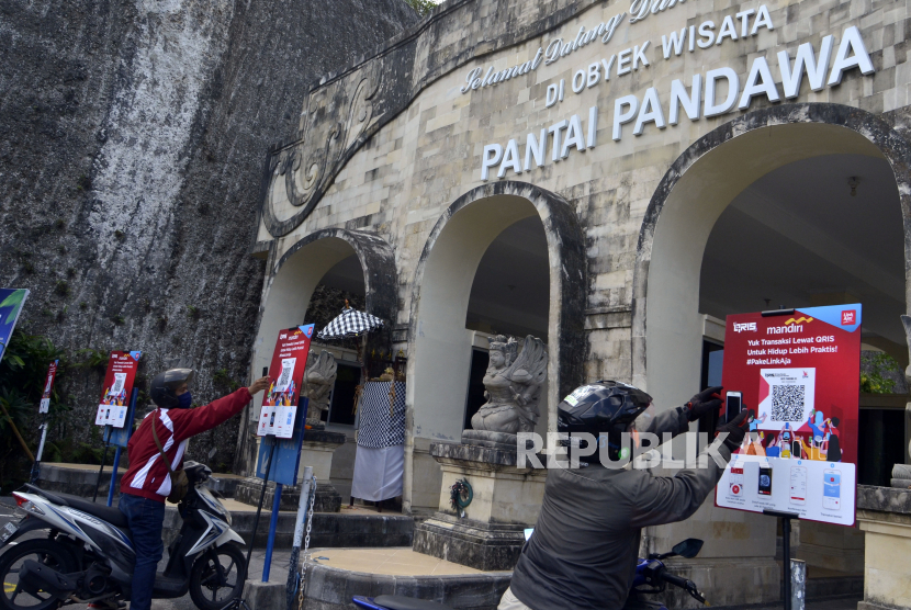 Pengunjung melakukan transaksi pembayaran berbasis digital dengan menggunakan Quick Response Code Indonesian Standard (QRIS) di Pantai Pandawa, Badung, Bali, Sabtu (11/7/2020). Bank Indonesia bekerjasama dengan Bank Mandiri, pengelola kawasan serta pemerintah daerah setempat meresmikan Pantai Pandawa sebagai kawasan wisata pantai digital berbasis QRIS yang menyediakan sistem pembayaran non-tunai untuk memudahkan wisatawan serta meminimalisir terjadinya kontak fisik guna mencegah penyebaran COVID-19.