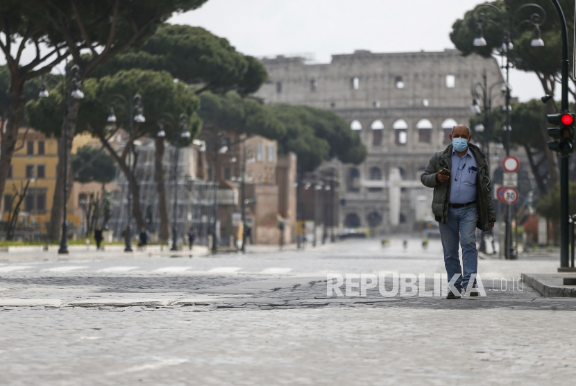 Seorang pria melintasi jalanan kosong dengan latar belakang Colosseum kuno pada saat lockdown Italia karena darurat virus Corona di Roma,  Ahad (29/3). Virus Corona baru menyebabkan gejala ringan atau sedang bagi kebanyakan orang, tetapi bagi sebagian orang, terutama orang tua dan orang dengan masalah kesehatan dapat menyebabkan penyakit yang lebih parah atau kematian