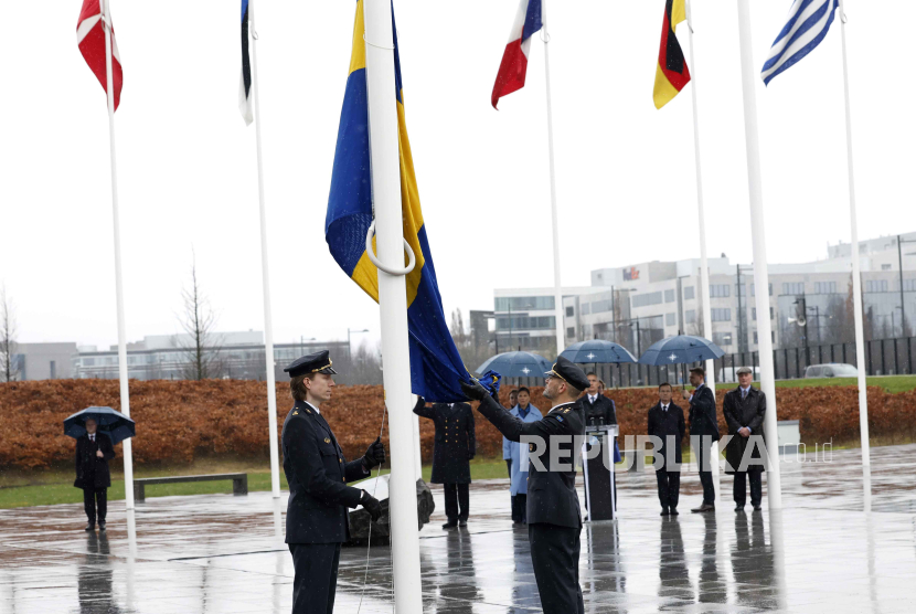 Anggota militer mengibarkan bendera Swedia dalam upacara menandai aksesi Swedia ke NATO di markas NATO di Brussels, Senin, (11/3/2024).