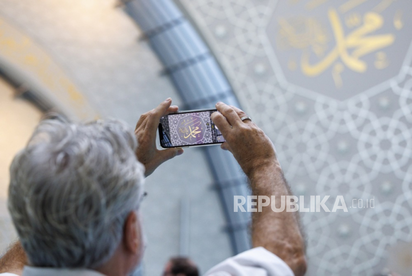 Seorang pengunjung mengambil foto kaligrafi di dalam Masjid Pusat Cologne saat Hari Masjid Terbuka di Cologne, Jerman, Selasa (3/10/2023).