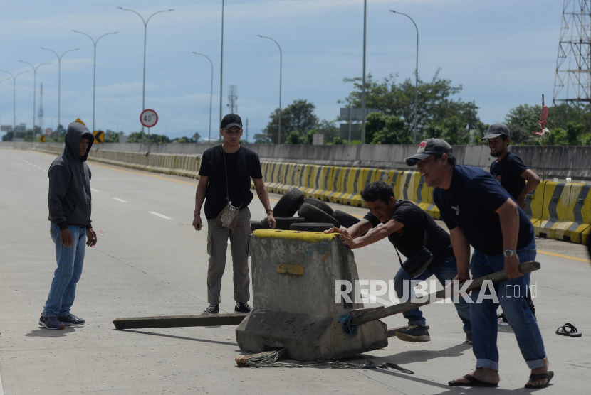 Warga memindahkan pembatas jalan saat aksi penutupan akses jalan menuju Gerbang Tol Jatikarya 2 di Jalan Tol Cimanggis-Cibitung, Kota Bekasi, Jawa Barat, Rabu (8/2/2023).