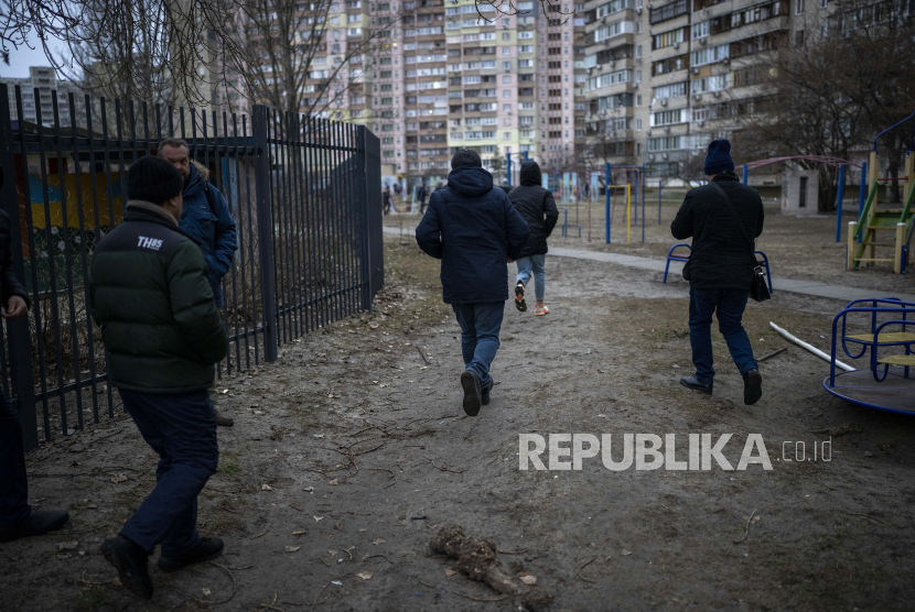  Orang-orang berlarian untuk berlindung sementara sirene berbunyi mengumumkan serangan baru di kota Kyiv, Ukraina, Jumat, 25 Februari 2022.