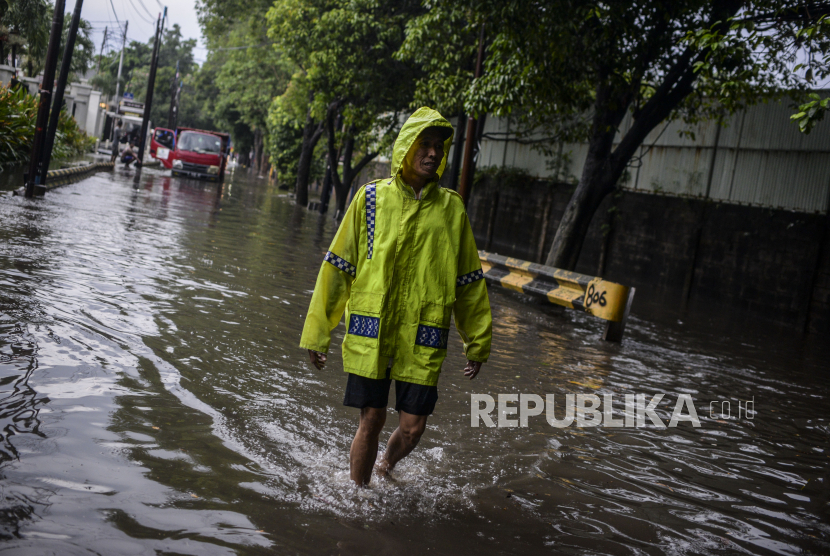 Warga berjalan melewati genangan air. ilustrasi