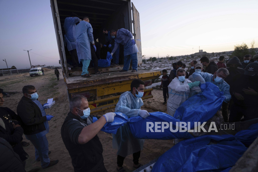 Petugas medis membongkar jenazah warga Palestina yang tewas dalam pertempuran dengan Israel dan diserahkan oleh militer Israel saat pemakaman massal di Rafah, Jalur Gaza, Selasa, (26/12/2023).