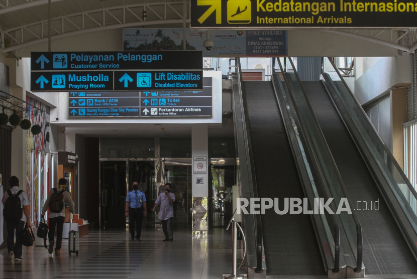 Sejumlah petugas dan calon penumpang menggunakan masker saat berada di area Bandara Sultan Syarif Kasim II yang terlihat sepi di Pekanbaru, Riau, Kamis (7/5/2020). 
