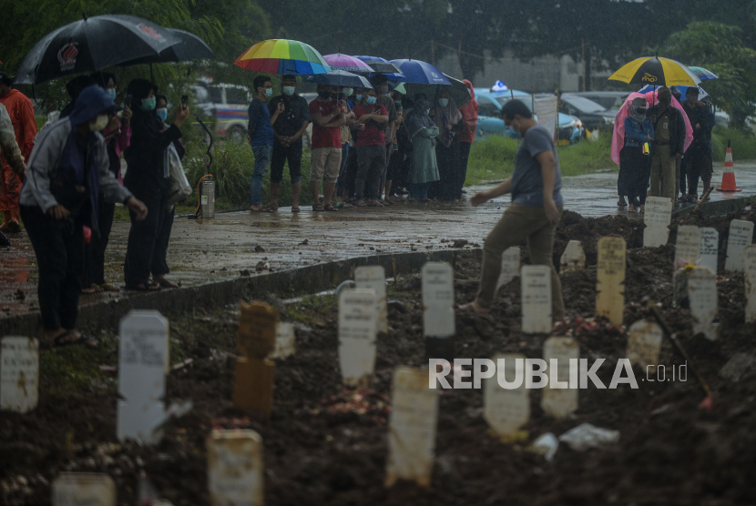 Keluarga dan kerabat melihat prosesi pemakaman jenazah pasien Covid-19 di TPU Bambu Apus, Jakarta, Selasa (16/2). 